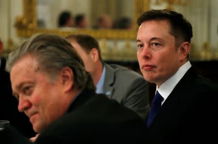 FILE PHOTO: Tesla CEO Elon Musk (R) sits beside Senior Counselor to the President Steve Bannon (L) as U.S. President Donald Trump hosts a strategy and policy forum with chief executives of major U.S. companies at the White House in Washington February 3, 2017. REUTERS/Kevin Lamarque