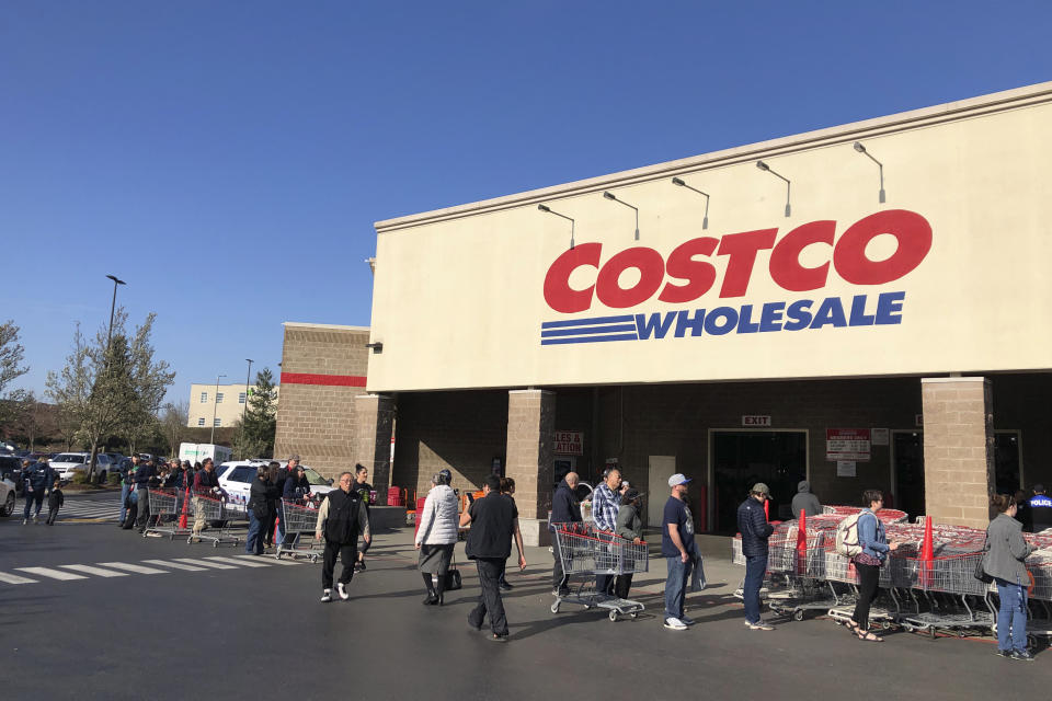 Shoppers line up to enter a Costco store, Friday, March 20, 2020, in Tacoma, Wash. Consumers continued to stock up on food and other items as officials urged people to stay at home to slow the spread of the new coronavirus. (AP Photo/Ted S. Warren)