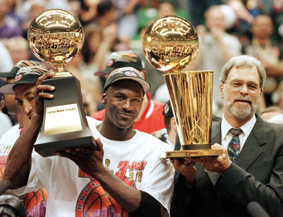 Michael Jordan (L) and Chicago Bulls head coach Phil Jackson (R) Most Valuable Player trophy (L) and the Larry O'Brian trophy (R) 14 June after winning game six of the NBA Finals with the Utah Jazz at the Delta Center in Salt Lake City, UT. The Bulls won the game 87-86 to take their sixth NBA championship.   AFP PHOTO Jeff HAYNES (Photo by JEFF HAYNES / AFP) (Photo by JEFF HAYNES/AFP via Getty Images)