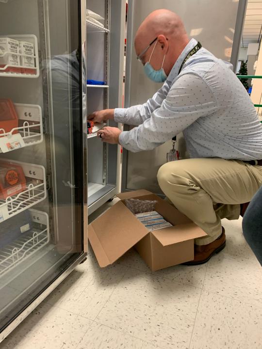 A staff member at the Fort Harrison VA Medical Center in Helena, Mont., places the Moderna COVID-19 vaccine in cold storage to be distributed. The medical center received its first shipment of the vaccine on Wednesday.