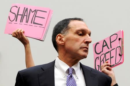 FILE PHOTO: Protestors hold signs behind Richard Fuld, Chairman and Chief Executive of Lehman Brothers Holdings, as he takes his seat to testify at a House Oversight and Government Reform Committee hearing on the causes and effects of the Lehman Brothers bankruptcy, on Capitol Hill in Washington, October 6, 2008. REUTERS/Jonathan Ernst/File Photo