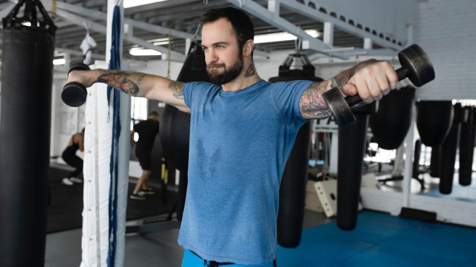 Man performs lateral raise with dumbbells