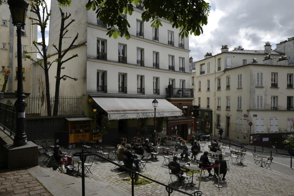 Customers sit at a cafe terrace in the Montmartre district of Paris, Wednesday, May, 19, 2021. Cafe and restaurant terraces reopened Wednesday after a six-month coronavirus shutdown deprived residents of the essence of French life — sipping coffee and wine with friends. (AP Photo/Rafael Yaghobzadeh)