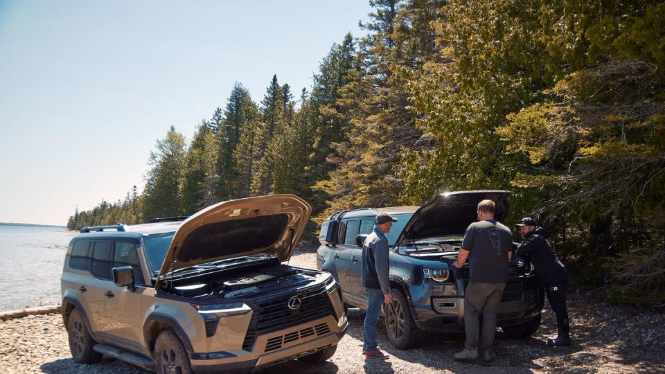 a group of men standing next to two vehicles with their hoods open