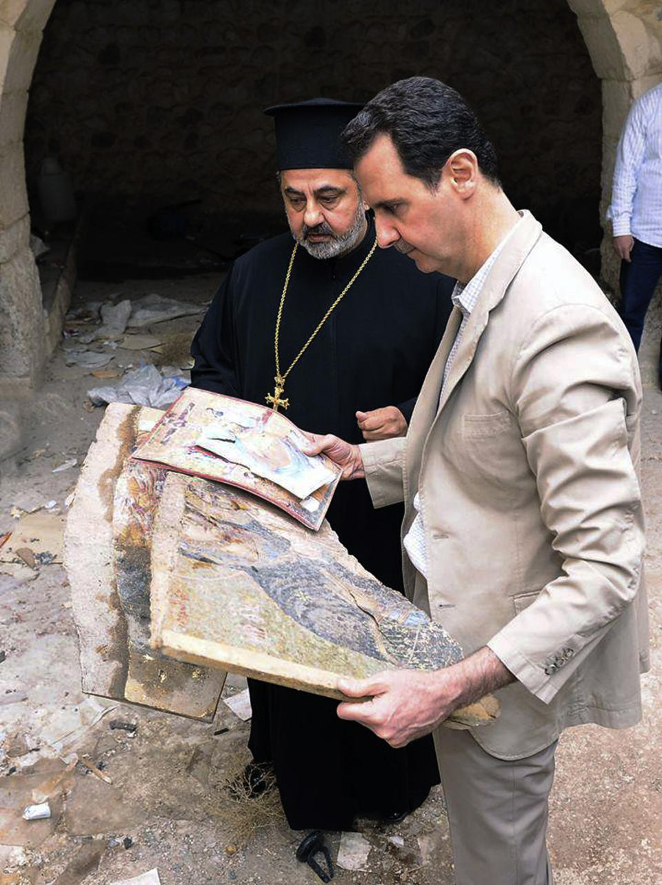 In this photo released by the Syrian official news agency SANA, Syrian President Bashar Assad, right, holds a broken religious mosaic during his visit to the Christian village of Maaloula, near Damascus, Syria, Sunday April, 20, 2014. Assad toured a historic Christian village his forces recently captured from rebels, state media said, as the country's Greek Orthodox Patriarch vowed that Christians in the war-ravaged country "will not submit and yield" to extremists. The rebels, including fighters from the al-Qaida-affiliated Nusra Front, took Maaloula several times late last year. (AP Photo/SANA)