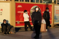 Residents wearing masks rest near propaganda posters on an empty plaza outside the train station in Beijing, Thursday, Dec. 8, 2022. In a move that caught many by surprise, China announced a potentially major easing of its rigid "zero-COVID" restrictions, without formally abandoning the policy altogether. (AP Photo/Ng Han Guan)