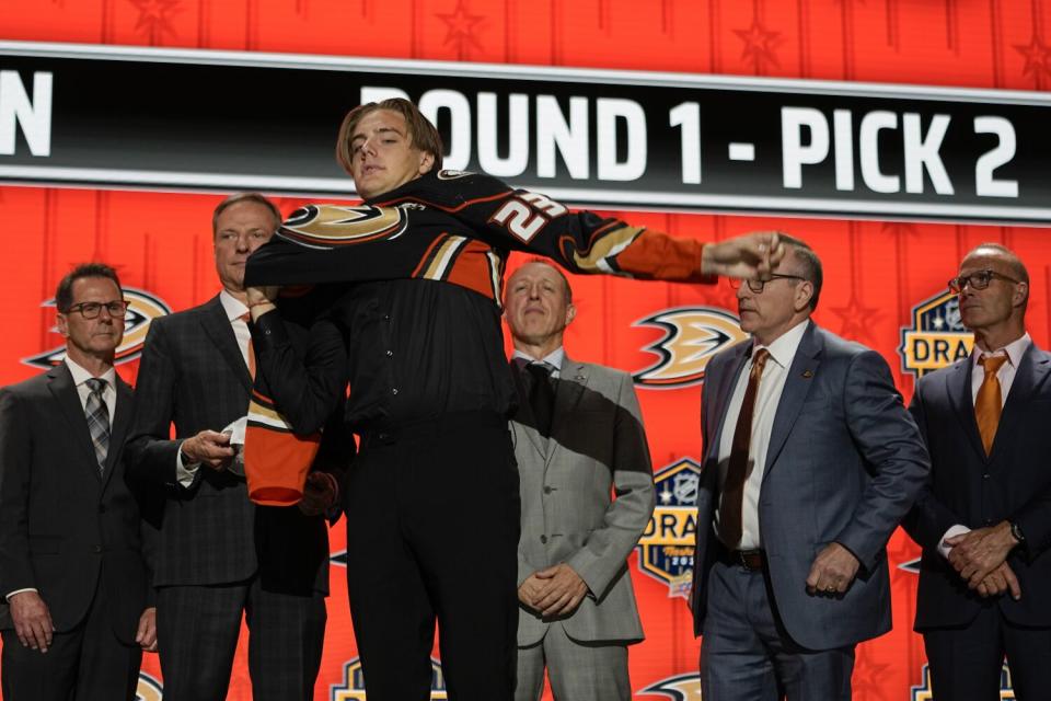 Leo Carlsson puts on a Ducks jersey after being picked by the team during the first round of the NHL draft.