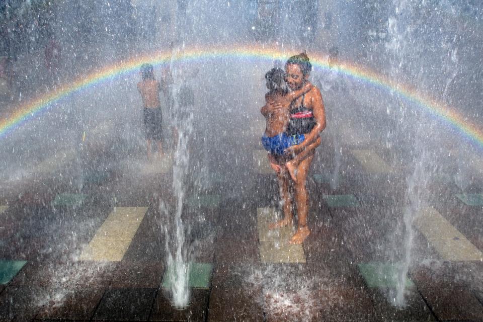 Nine-year-old Candace Jones of Stockton, carrying her four-year-old brother Kyle, cools off in the jest of water at the interactive fountain at the Weber Point Event center in downtown Stockton on August 3, 2007. 
