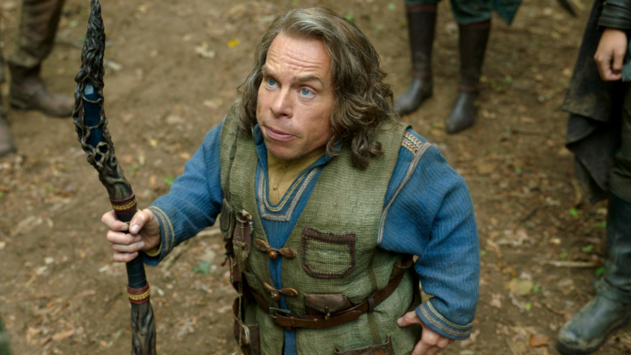  Warwick Davis holding a magical staff in the woods in Willow. 