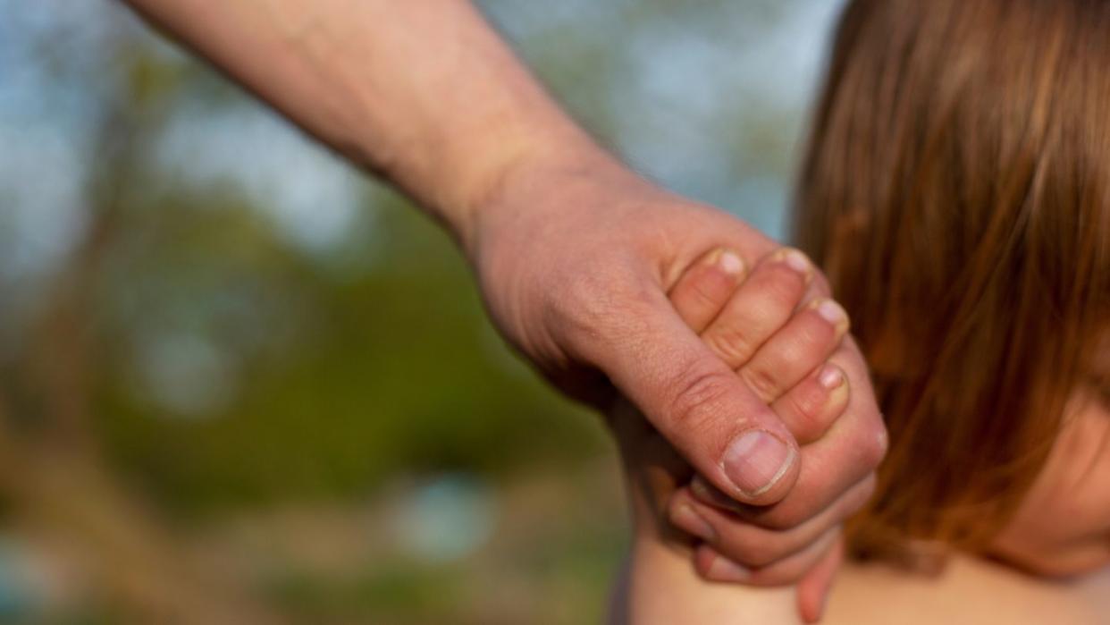 Ein junger Vater hält am Strand eines Sees die Hand seines kleinen Sohnes. Die Zahl der Neugeborenen in Europa und den USA ist wegen der Corona- Pandemie teilweise deutlich zurückgegangen.