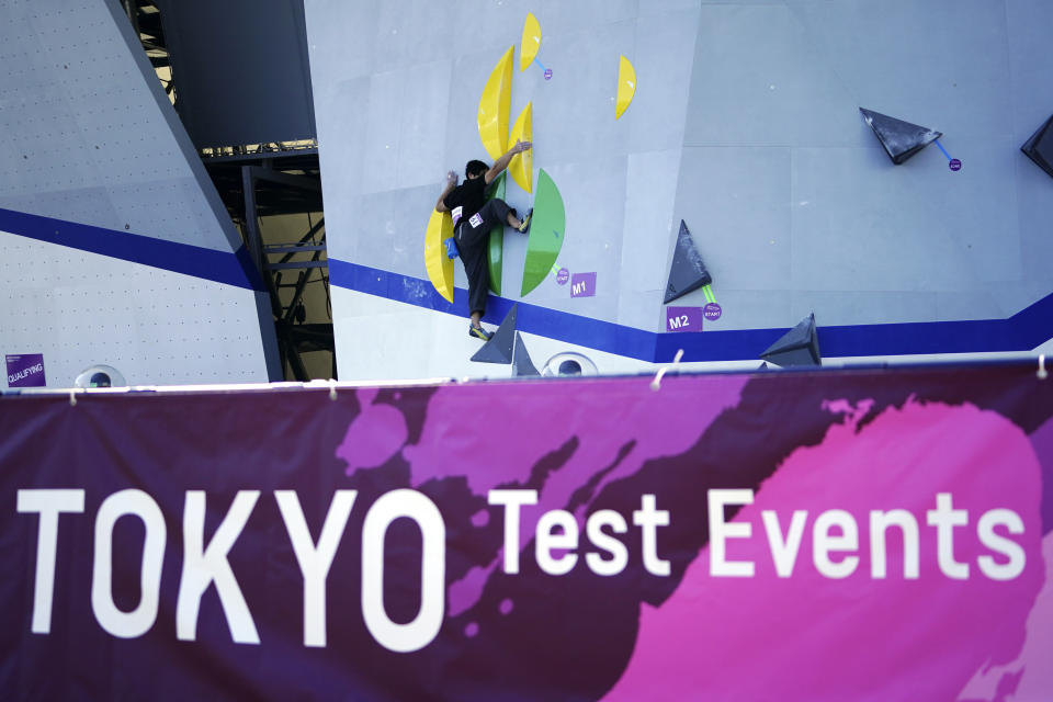 FILE - In this Friday, March 6, 2020, file photo, a Tokyo 2020 Olympic Games Organizing staff climbs the wall in the test event of Speed Climbing in preparation for the Tokyo 2020 Olympic Games at Aomi Urban Sports Park in Tokyo. The tentacles of cancelling the Tokyo Olympics — or postponing or staging it in empty venues — would reach into every corner of the globe, much like the spreading virus that now imperils the opening ceremony on July 24. (AP Photo/Eugene Hoshiko, File)