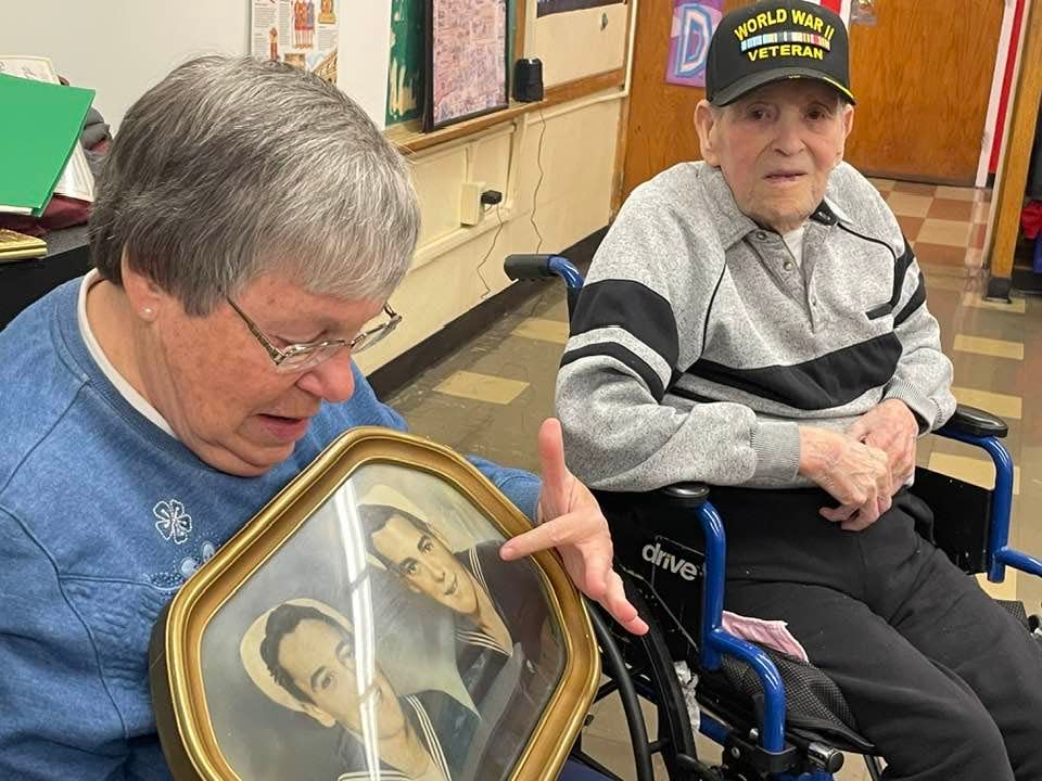 St. James School teacher Jackie Lajoie and her WWII Navy veteran father Roland "Pete" Lajoie look at an old photograph of him and his brother, dressed in their uniforms. Roland Lajoie is the last living WWII veteran in Thompson.