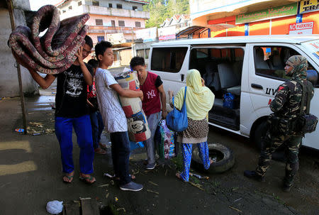 A government soldier looks on evacuees with their belongings while manning a checkpoint at a main street of Marawi city, after government troops' continuous assault with insurgents from the so-called Maute group, who has taken over large parts of the city, in Marawi City, southern Philippines May 27, 2017. REUTERS/Romeo Ranoco