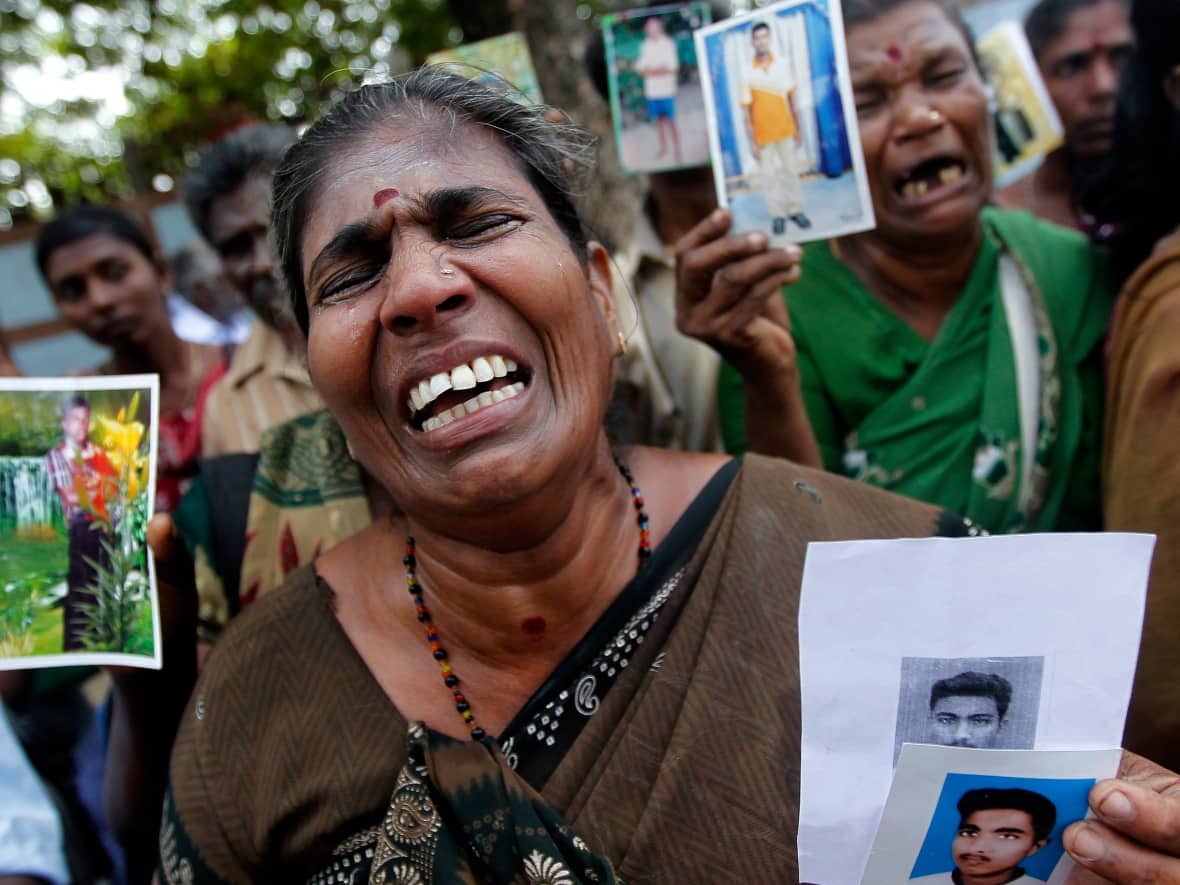 A Tamil woman holds up a photo of her disappeared family member at a protest in 2013, several years after the end of the country's civil war. Many of the victims' families are still searching for answers, and some activists are now calling for more accountability in the wake of ex-president Gotabaya Rajapaksa's resignation. (Dinuka Liyanawatte/Reuters - image credit)