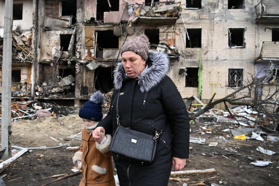 A woman and child walk through a residential area of Kyiv in the second day of the invasion (AFP/Getty)