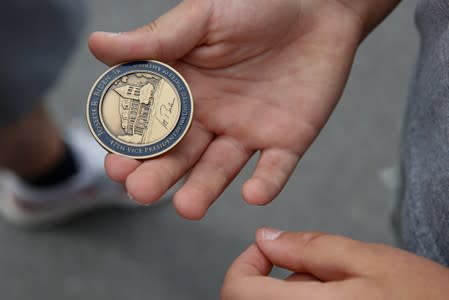 A boy holds out a challenge coin given to him by Democratic 2020 U.S. presidential candidate and former Vice President Joe Biden outside Lindy's Diner in Keene