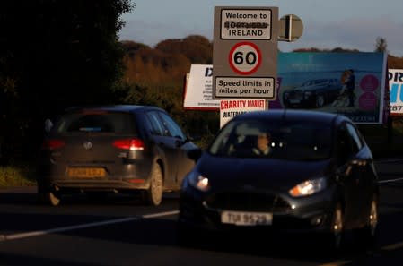 Vehicles pass a defaced roadsigns at the border between Ireland and Northern Ireland near Bridgend, Northern Ireland