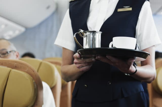 Flight attendant holding tray with coffee, mid section