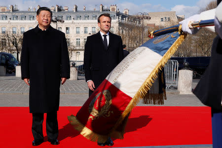 French President, Emmanuel Macron and his Chinese counterpart, Xi Jinping stand to attention as they review an honour guard prior to a wreath laying ceremony at the Arc de Triomphe monument in Paris, France March 25, 2019. Francois Mori/Pool via REUTERS