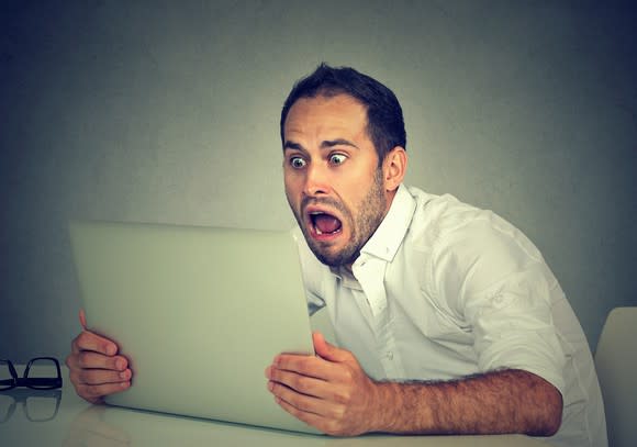 Man with wide eyes and open mouth looking at a large tablet screen