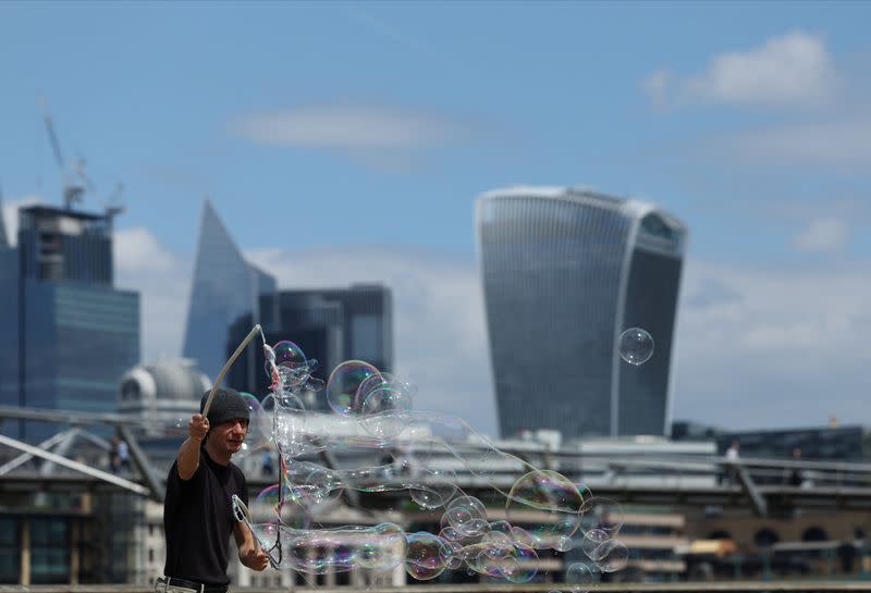 A street performer makes soap bubbles in front of the Financial District on the Southbank