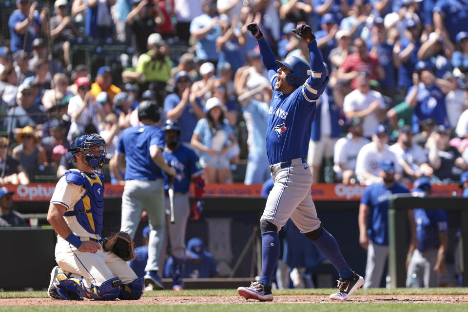 Toronto Blue Jays' George Springer, right, celebrates at home plate after hitting a three-RBI home run as Seattle Mariners catcher Cal Raleigh looks on during the seventh inning of a baseball game, Sunday, July 7, 2024, in Seattle. (AP Photo/Jason Redmond)