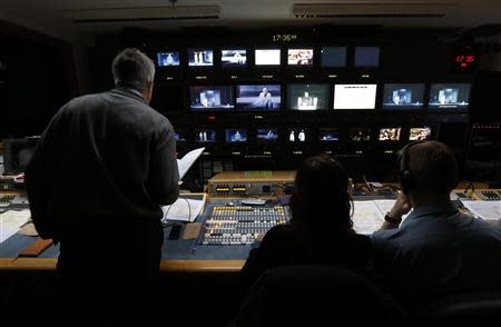 Director Jonathan Haswell (L) watches a video feed in the media suite as the broadcast team works during a live transmission of the opera "Parsifal" from the Royal Opera House in London December 18, 2013. REUTERS/Suzanne Plunkett