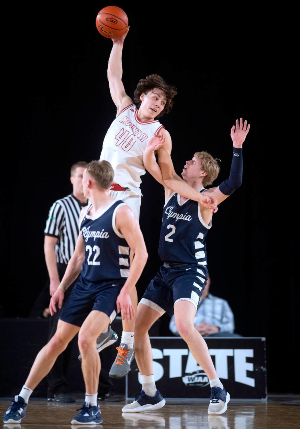 Mount Si’s Miles Heide pulls down a pass over Olympia defenders Parker Gerrits (22) and Andreas Engholm during their state semifinal game at the WIAA state basketball tournament in the Tacoma Dome in Tacoma, Washington, on Friday, March 3, 2023.