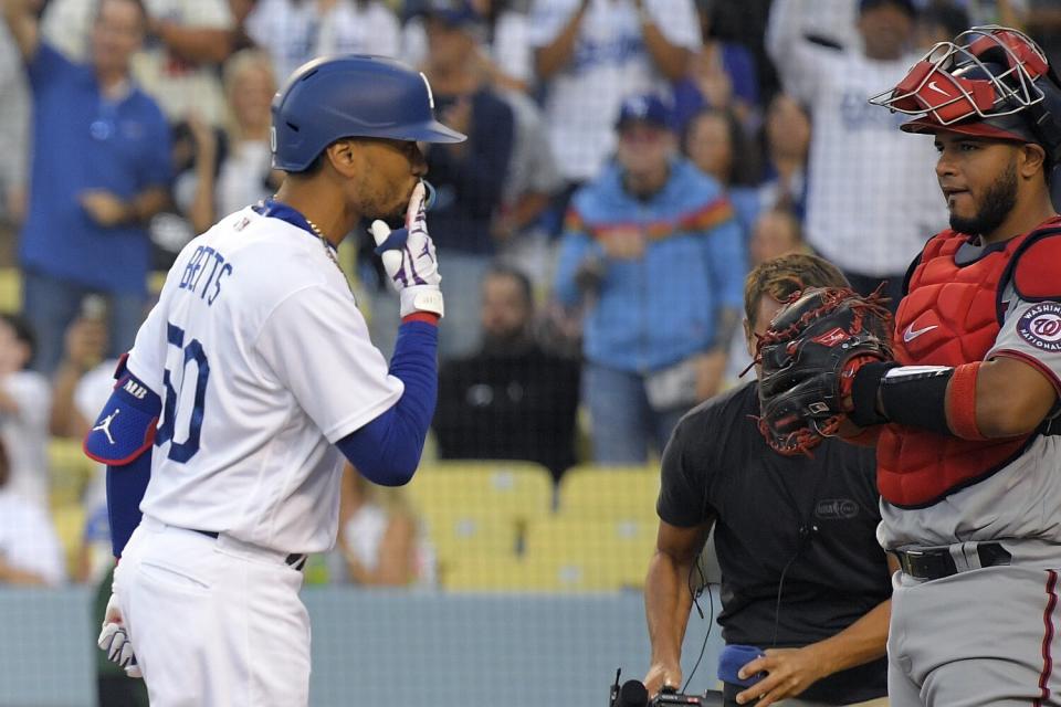 Dodgers' Mookie Betts blows a kiss toward the crowd as Washington Nationals catcher Keibert Ruiz watches.