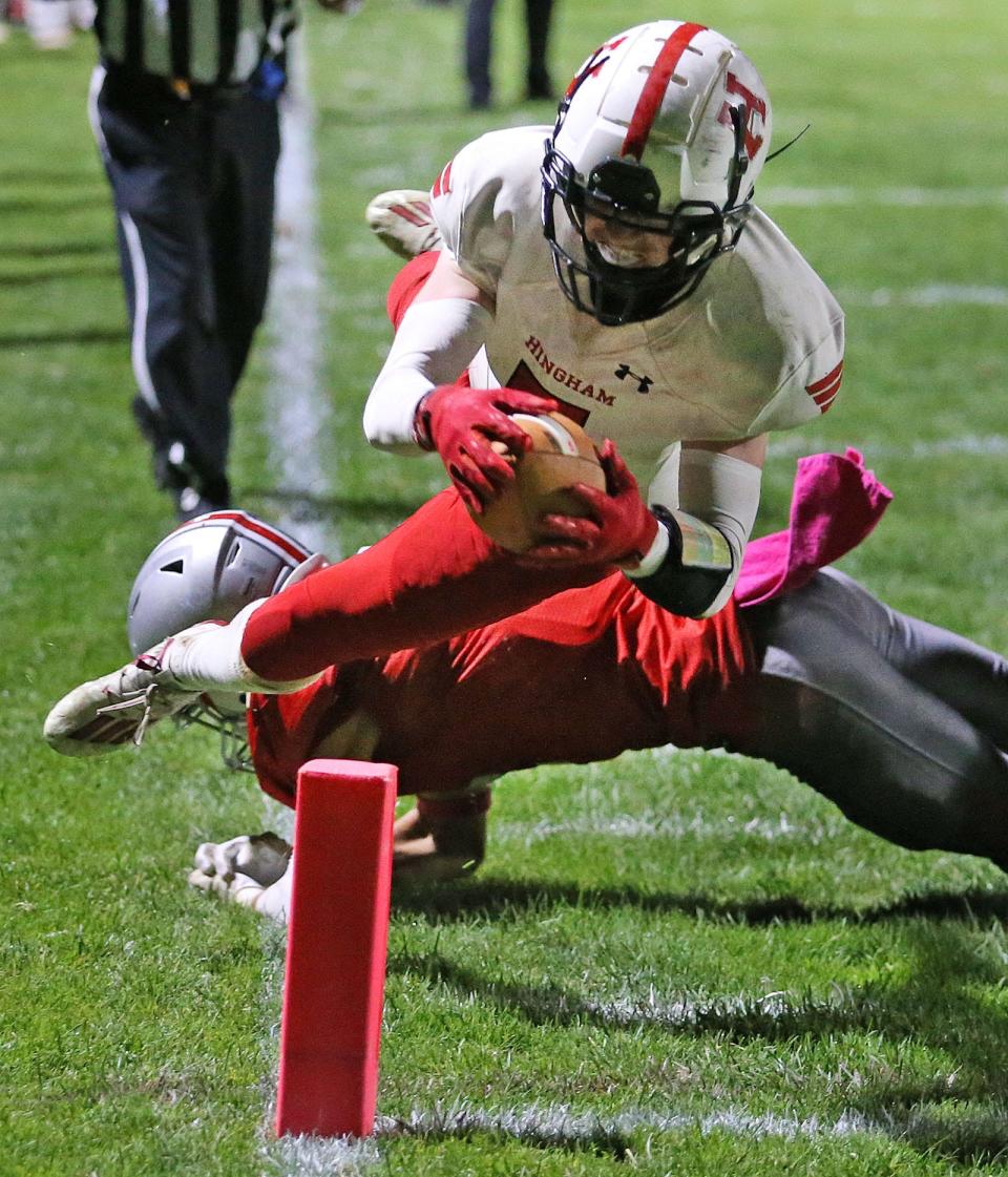 Hingham's Brendan Hill jumps over Silver Lake's Ryan Green to stay inbounds and score a touchdown.
