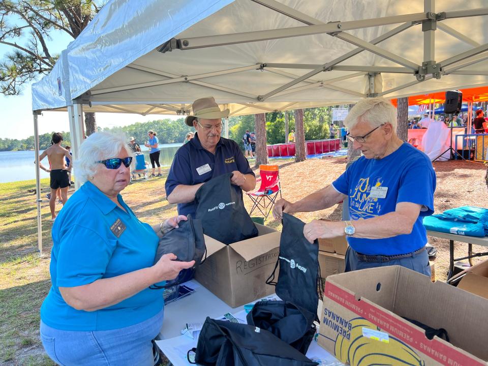 Southport Rotary Club members Merry McBarb, Peter Braun, and Bill Jenkins work to fill goodie bags at the Go Jump in the Lake 5K on Monday, Sept. 4.