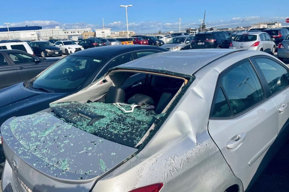 A damaged car is seen at an on-airport employee parking lot after tyre debris from a Boeing 777 landed on it (AP)