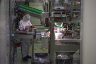 In this Thursday, Feb. 27, 2020, photo, a worker checks yogurt coming off the production line at the Mengniu dairy factory in Beijing. Reporters were invited to China Mengniu Dairy Co. Ltd. this week to be shown how companies are reviving after anti-virus measures shut down most of the world's second-biggest economy. (AP Photo/Ng Han Guan)