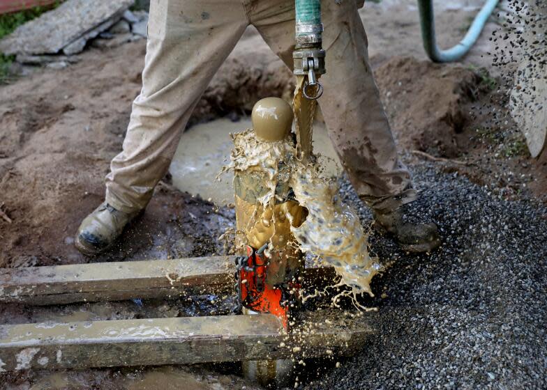 SANGER, CA - FEBRUARY 22: Julio Morales, foreman for H&B Drilling and Sons, places gravel around a newly drilled 240-ft water well, on the property of Tom Cook, 55, not shown, homeowner, along Central Ave., in the Tombstone neighborhood, unincorporated Fresno County, on Wednesday, Feb. 22, 2023 in Sanger, CA. Cook has an agency transport non-potable water to a 2500 gallon tank located on his property. Tom had a 70-ft well that went dry in Aug. 2022, the same year he purchased the home. He spent around $30,000 for the new well. In the community of Tombstone in Fresno County, residents' wells have continued going dry during the drought as nearby farms have heavily pumped groundwater, drawing down the water levels. Residents have lost access to water and are now depending on tanks and deliveries of water by truck. A potential solution for the area would involve connecting to water pipes from nearby Sanger, but progress has been slow. (Gary Coronado / Los Angeles Times)