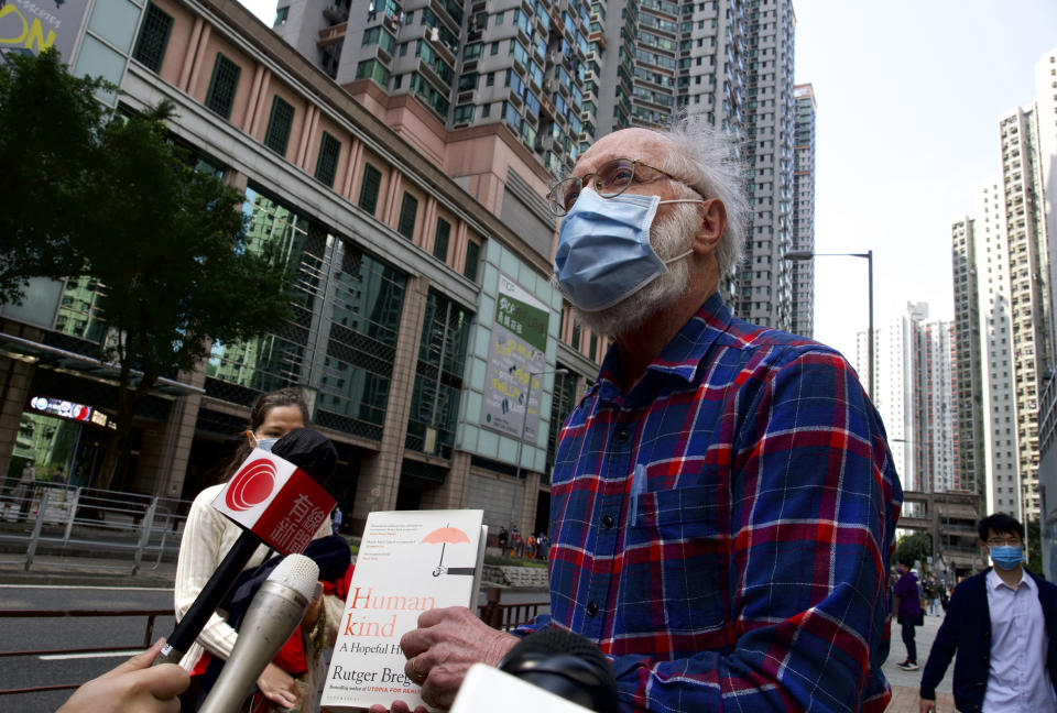 John Clancey, an American lawyer who became the first foreigner arrested under Hong Kong's national security law, displays a book before appearing at a police station in Hong Kong Sunday, Feb. 28, 2021. Clancey appeared at a police station Sunday, following a surprise request from police Friday. (AP Photo/Vincent Yu)