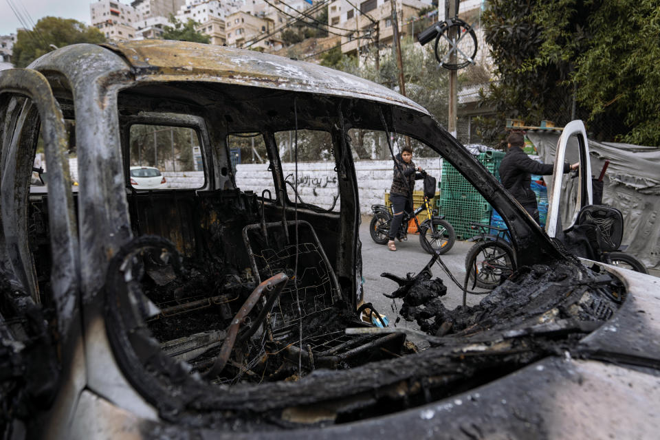 Palestinians look at a damaged car following clashes between Israel army and Palestinians during an Israeli raid in the occupied West Bank city of Nablus, Tuesday, Oct. 25, 2022. The military says Israeli forces have raided a stronghold of an armed group in the West Bank, blowing up an explosives lab and engaging in a firefight. Palestinian health officials say five Palestinians were killed and 20 were wounded. The target of the raid was a group calling itself the Lions' Den, accused by Israel of having killed a soldier and attempting several attacks. (AP Photo/Majdi Mohammed)