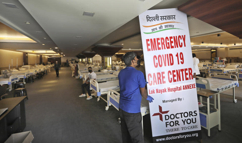 Health workers put up a banner before the opening of a COVID-19 care center at a banquet hall, in New Delhi, India, Tuesday, June 23, 2020. Some states Tuesday were considering fresh lockdown measures to try to halt the spread of the virus in the nation of more than 1.3 billion. (AP Photo/Manish Swarup)