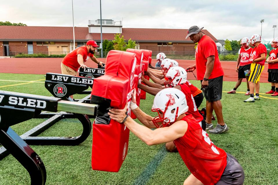 New Bedford High linemen work the sled at preseason training.