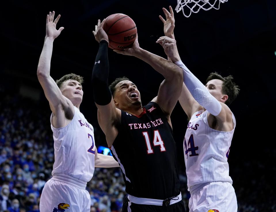 Texas Tech Marcus Santos-Silva (14) is fouled while shooting by Kansas' Christian Braun (2) and Mitch Lightfoot (44) during the second half of a Big 12 Conference game Tuesday at Allen Fieldhouse in Lawrence, Kansas.