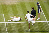 Serbia's Novak Djokovic steps over the net to check on the condition of Italy's Jannik Sinner who slipped while chasing down a ball in a men's singles quarterfinal match on day nine of the Wimbledon tennis championships in London, Tuesday, July 5, 2022. (AP Photo/Alberto Pezzali)