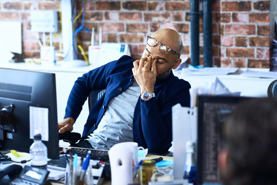 Tired man sitting at desk in modern office