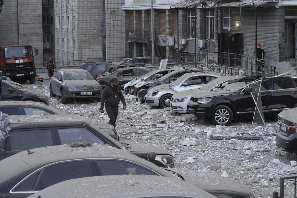 Un agente de policía camina por un estacionamiento con autos dañados, frente a un edificio de varias plantas, luego de un ataque ruso sobre Kiev, en Ucrania, el 30 de mayo de 2023. (AP Foto/Roman Hrytsyna)