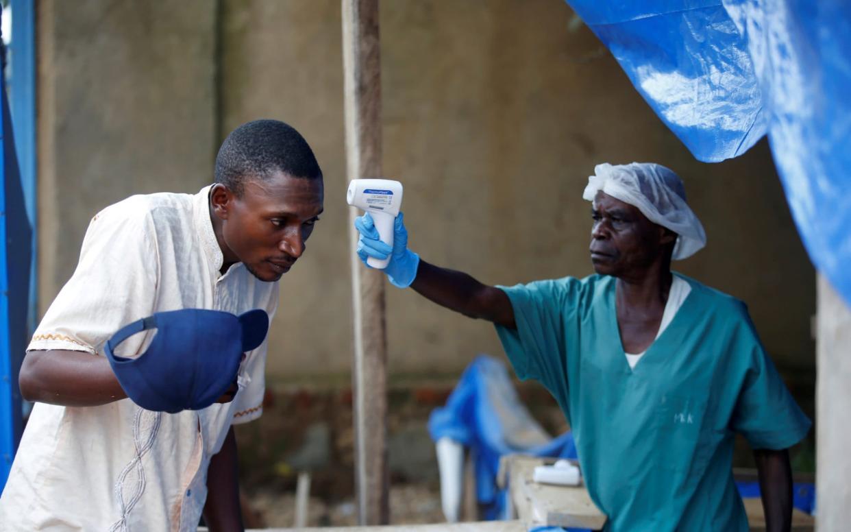 A health worker takes the temperature of a man entering an Ebola treatment centre - REUTERS