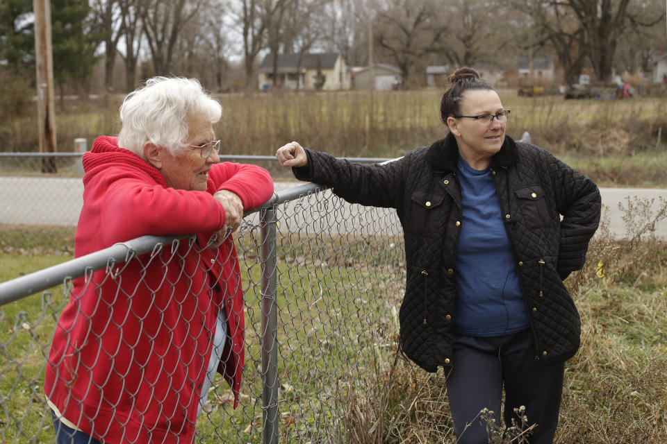 In this photo taken Monday, Nov. 18, 2019, Tammy Kilgore, right, talks to her neighbor Betty Cazzell after Kilgore's home was demolished in Mosby, Mo. Kilgore accepted a $45,000 voluntary buyout offer to leave her flood-prone home of 38 years and has moved to a nearby community. (AP Photo/Charlie Riedel)