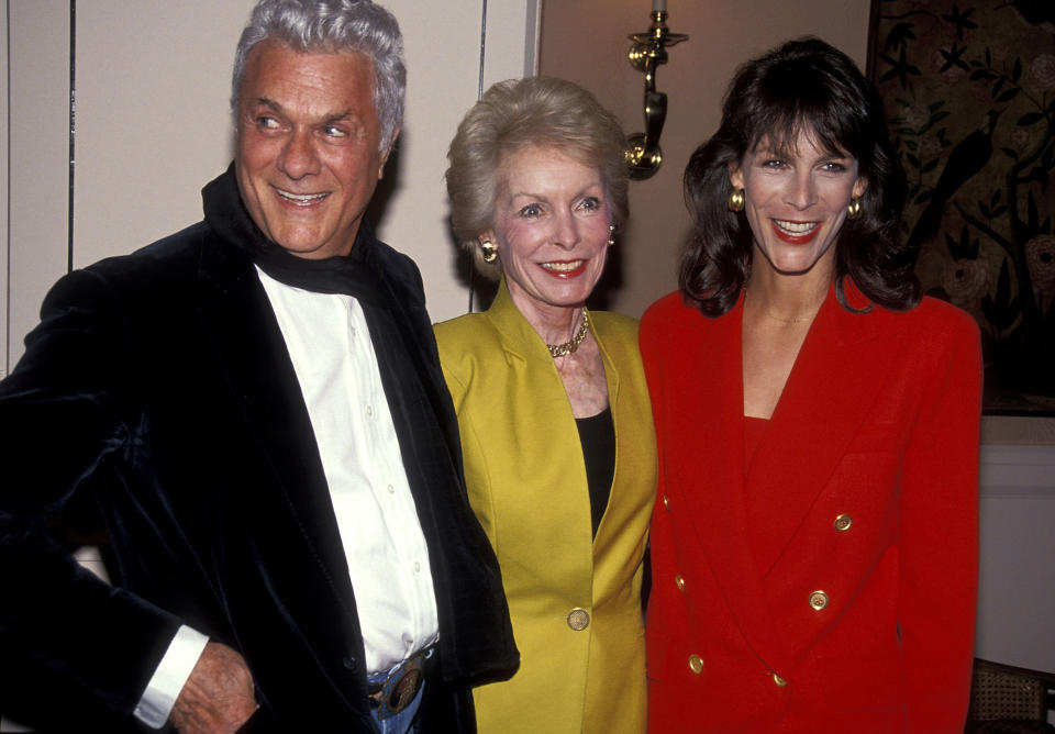 Three individuals posing together, two men flanking a woman; each wears formal attire