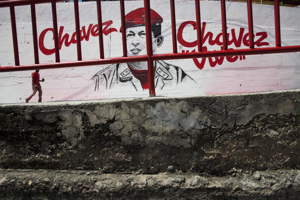 Un hombre camina frente a un mural del expresidente de Venezuela Hugo Chávez en Caracas, Venezuela, el martes cuatro de marzo de 2014. El exmandatario lleva un año de muerto pero su rostro y su voz están por doquier. Su voz suena en la radio estatal entonando el himno nacional todas las mañanas. Con motivo de la muerte de Chávez el presidente Nicolás Maduro ha decretado diez días de conmemoración que, en total, suman tres días más que el período de luto oficial concedido una semana después de su muerte. Chávez murió a los 58 años, el 5 de marzo de 2013. (AP Foto/Rodrigo Abd)