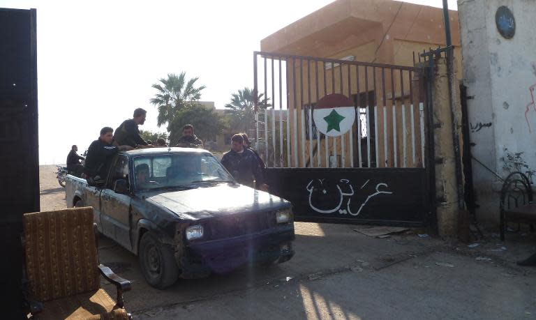 Syrian rebel fighters drive through the gate of the Syrian Government army Base 46 after its capture, near the northern city of Aleppo, on November 21, 2012