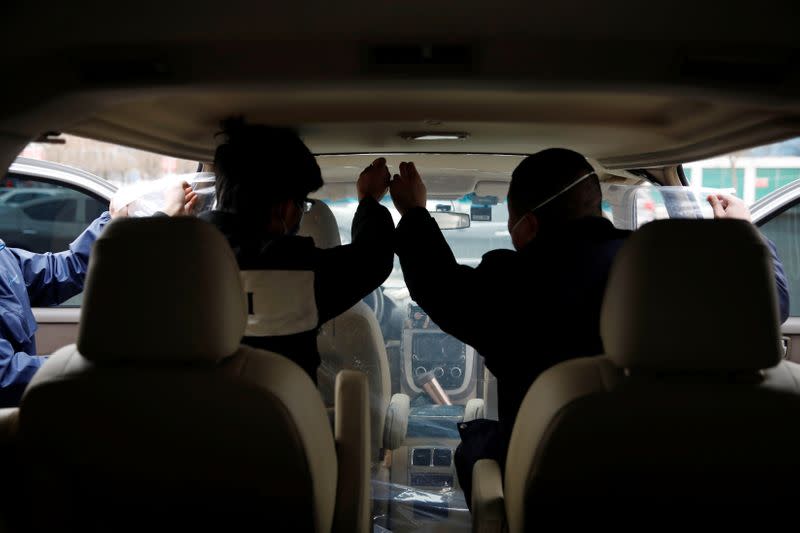 Staff members install plastic shield inside a vehicle at a service centre of car-hailing service Didi Chuxing, as the country is hit by an outbreak of the new coronavirus, in Beijing