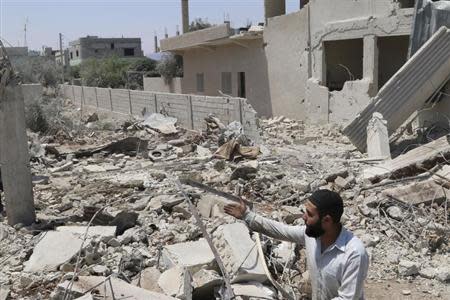 A man inspects a site hit by what activists say was a barrel bomb dropped by forces loyal to Syria's President Bashar al-Assad in Saida village in the eastern countryside of Deraa May 11, 2014. REUTERS/Mohamed Fares