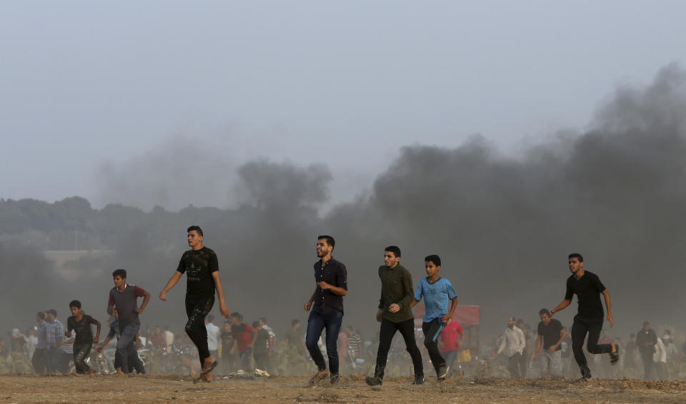 Protesters run to inspect the site of an Israeli airstrike near the Gaza Strip border with Israel east of Khan Younis, southern Gaza Strip, Friday, Oct. 19, 2018. (AP Photo/Adel Hana)